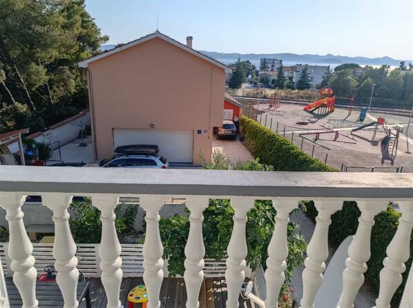 A residential building with a garage, a playground with slides, and a view of mountains in the background.