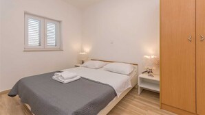 Ein Schlafzimmer mit Bett, Nachttischlampen, einem Fenster und einem Kleiderschrank.