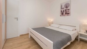 Ein Schlafzimmer mit Bett, Nachttisch, Wandleuchte und einer Tür.