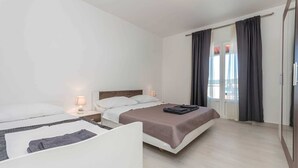 Ein Hotelzimmer mit zwei Betten, einem Kleiderschrank und einem großen Fenster mit Vorhängen.