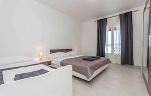 A hotel room with two beds, a wardrobe, and a large window with curtains. - Beachfront Apt. Sunset 1 (Turanj)