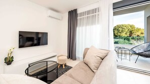 Ein modernes Wohnzimmer mit einer Couch, einem Fernseher, einem kleinen Tisch und einem Sessel.