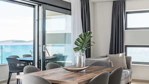 Una sala de estar moderna con comedor, ventanas amplias y vista al mar.