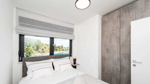 Un dormitorio moderno con una cama grande, vistas a una piscina y un armario gris.