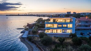 A modern two-story building with multiple balconies overlooking a waterfront. - Beachfront Villa Fresca (F4) Penthouse 6+1 guests (Bibinje)