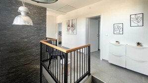 Un interior moderno con una escalera, una lámpara fijada a la pared y obras de arte.