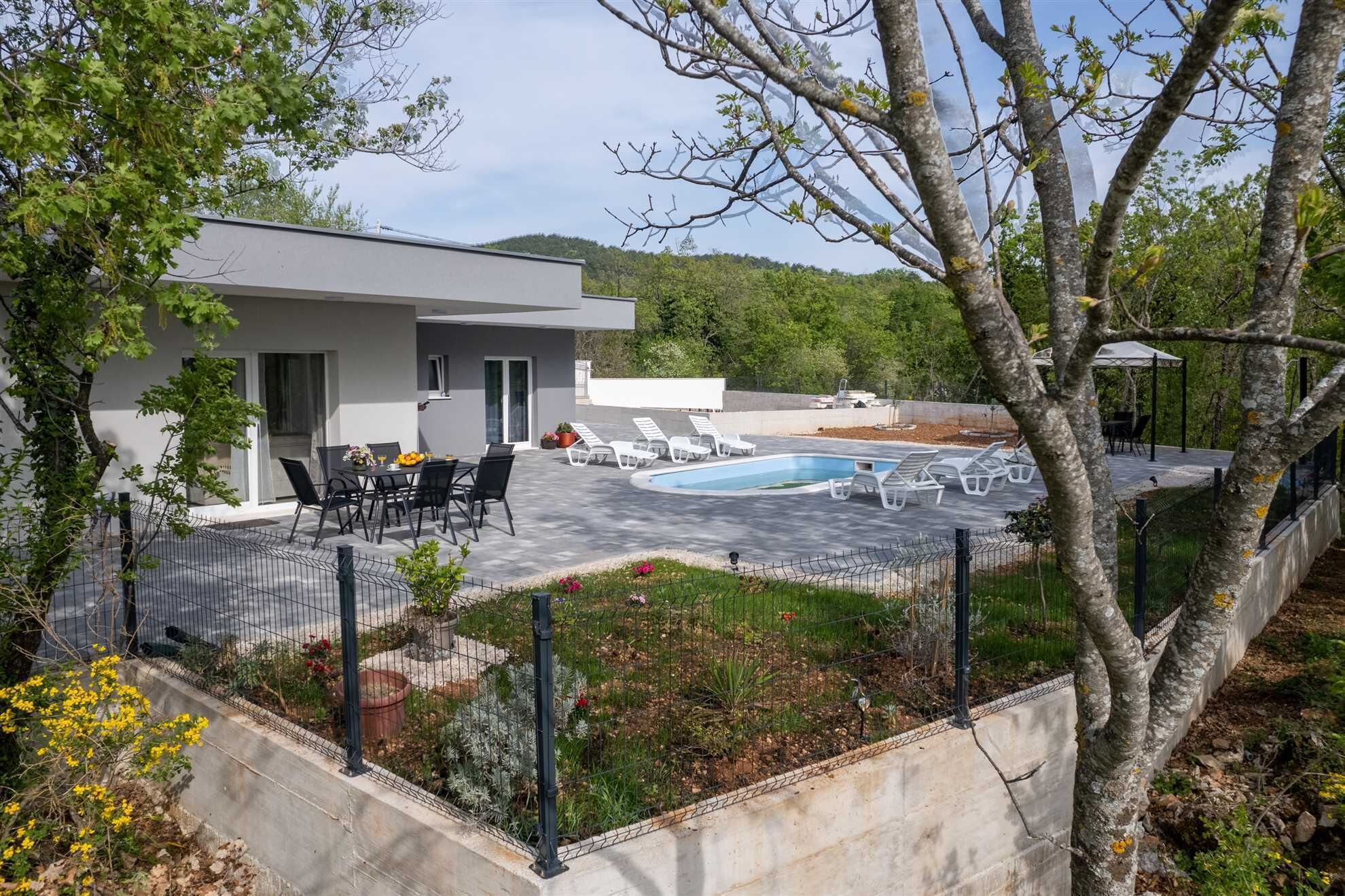 A modern house with a swimming pool, outdoor seating, and a garden area.
