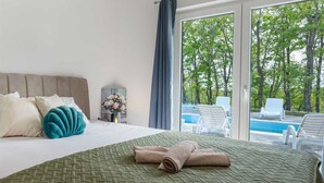 Una habitación de hotel con cama, vista a una piscina y mobiliario exterior.