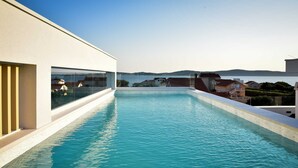 Una piscina infinita moderna con vistas claras al mar y edificios circundantes.