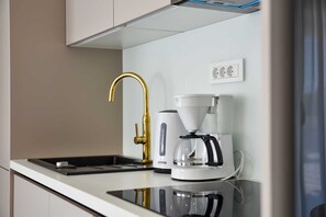 A modern kitchen with a gold faucet, a white coffee maker, and a black stove top. - Apartment with rooftop pool A1, Bibinje (Bibinje)