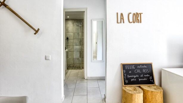 A hallway with a shower, a wooden stool, and a chalkboard with text. - Villa 'Masia Cal Ros' with Mountain Views, Wi-Fi, and Air Conditioning (S'Agaró)