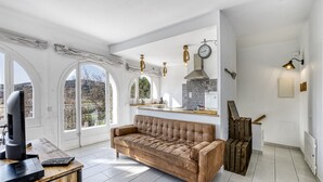 A modern living room with a leather sofa, a flat-screen TV, and a wooden desk. - Villa 'Masia Cal Ros' with Mountain Views, Wi-Fi, and Air Conditioning (S'Agaró)