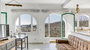 A spacious room with a large window, a sofa, a dining table, and a TV. - Villa 'Masia Cal Ros' with Mountain Views, Wi-Fi, and Air Conditioning (S'Agaró)
