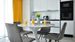 Eine moderne Küche mit weißen Schränken, einem schwarzen Backofen und einer Kaffeemaschine auf der Arbeitsfläche.