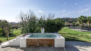 Een hottub met trap, omringd door groen en uitzicht op een stad in de verte.