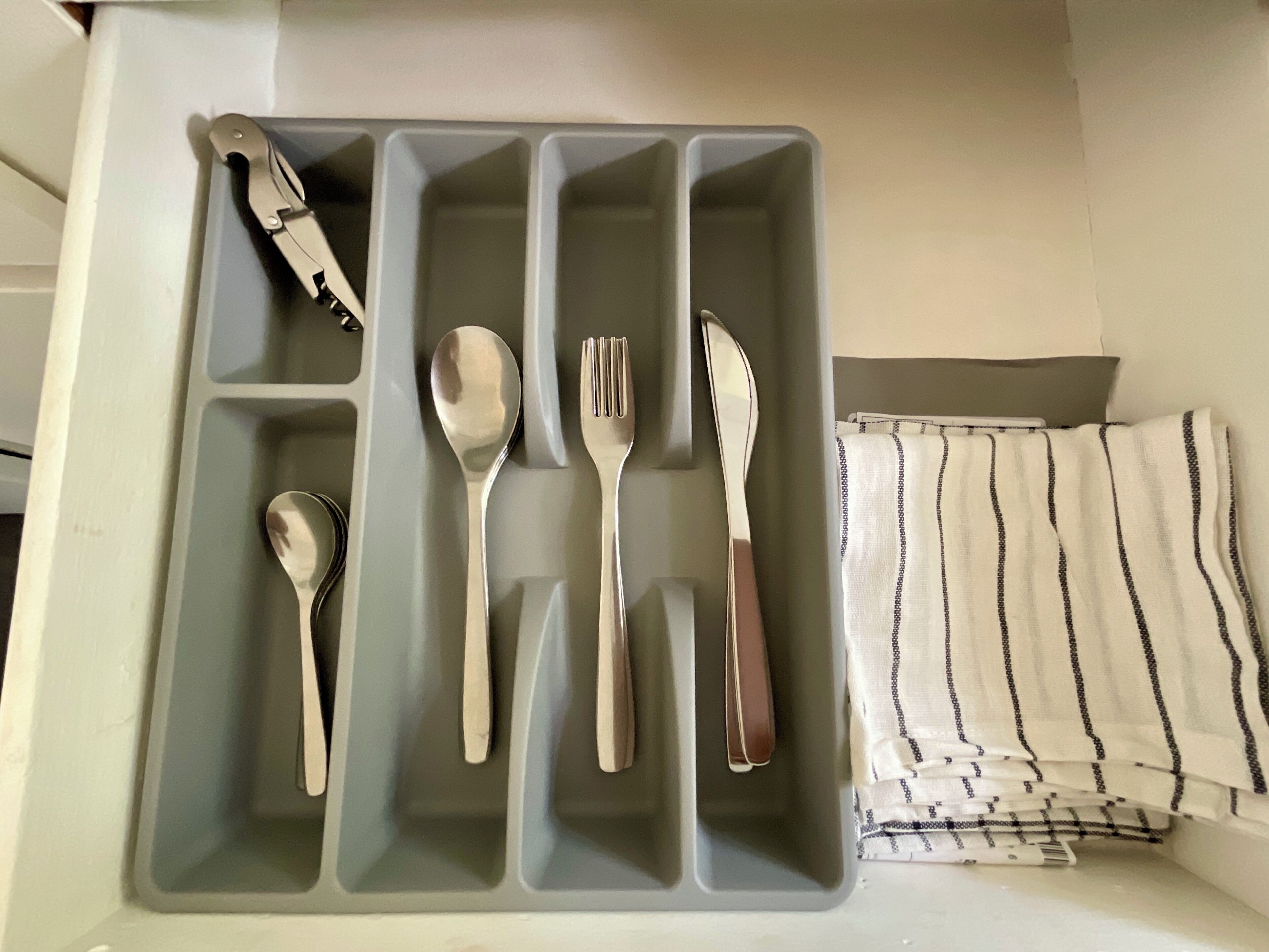 A gray tray with utensils and a striped cloth.