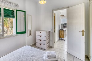 Un dormitorio con una cama, un tocador, un espejo y una puerta que da a un balcón.