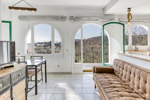 Una habitación amplia con un gran ventanal, un sofá, una mesa de comedor y un televisor.