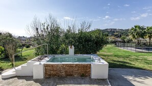 Een hottub met treden, omgeven door groen en met uitzicht op een stad in de verte.