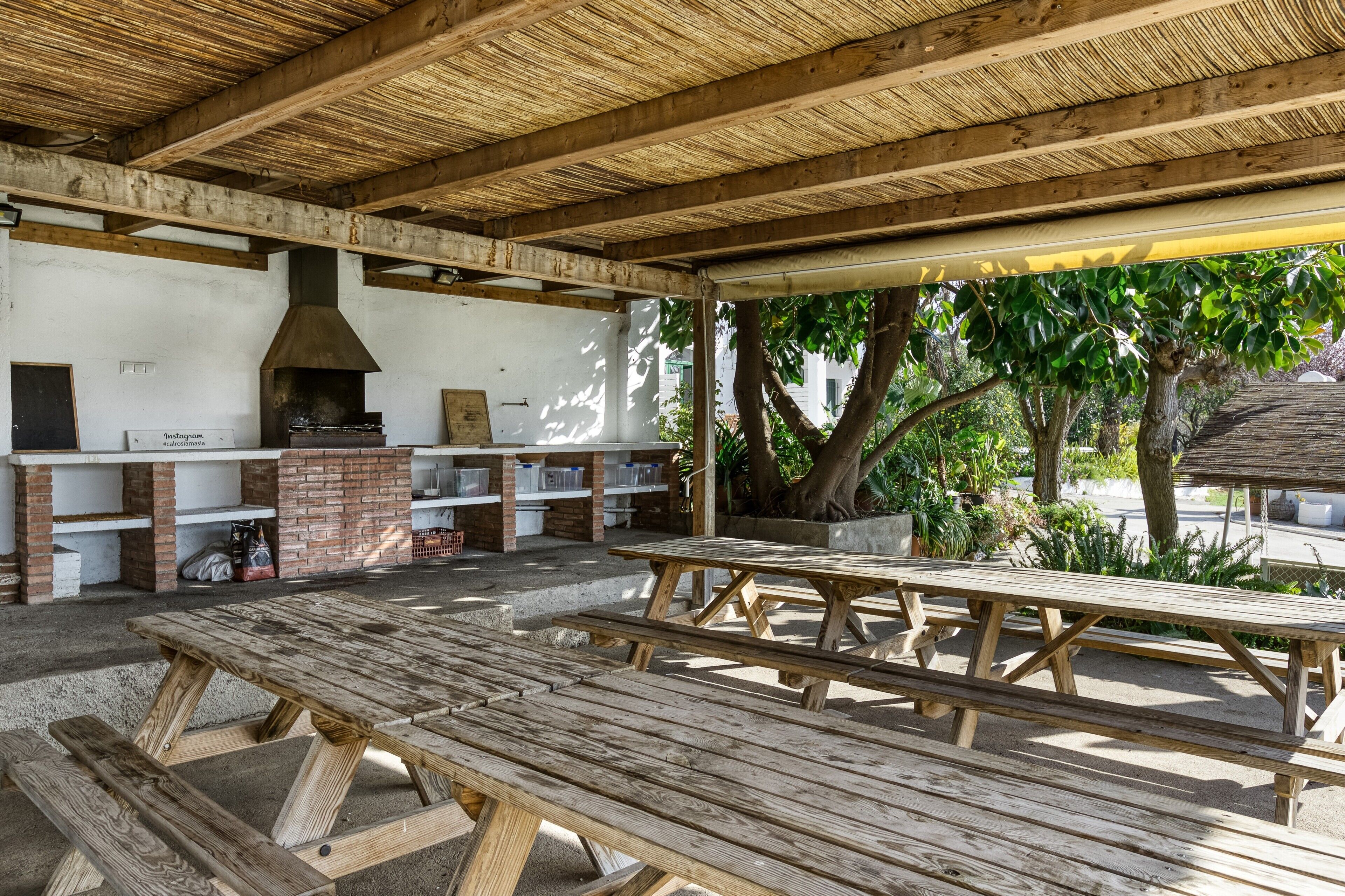 Eine Terrasse im Freien mit Holzbänken und einer Grillstelle aus Ziegeln.