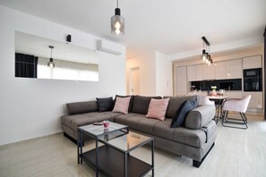 A modern living room with a sofa, coffee table, and pendant lights. - Apartment with rooftop pool A2, Bibinje (Bibinje)