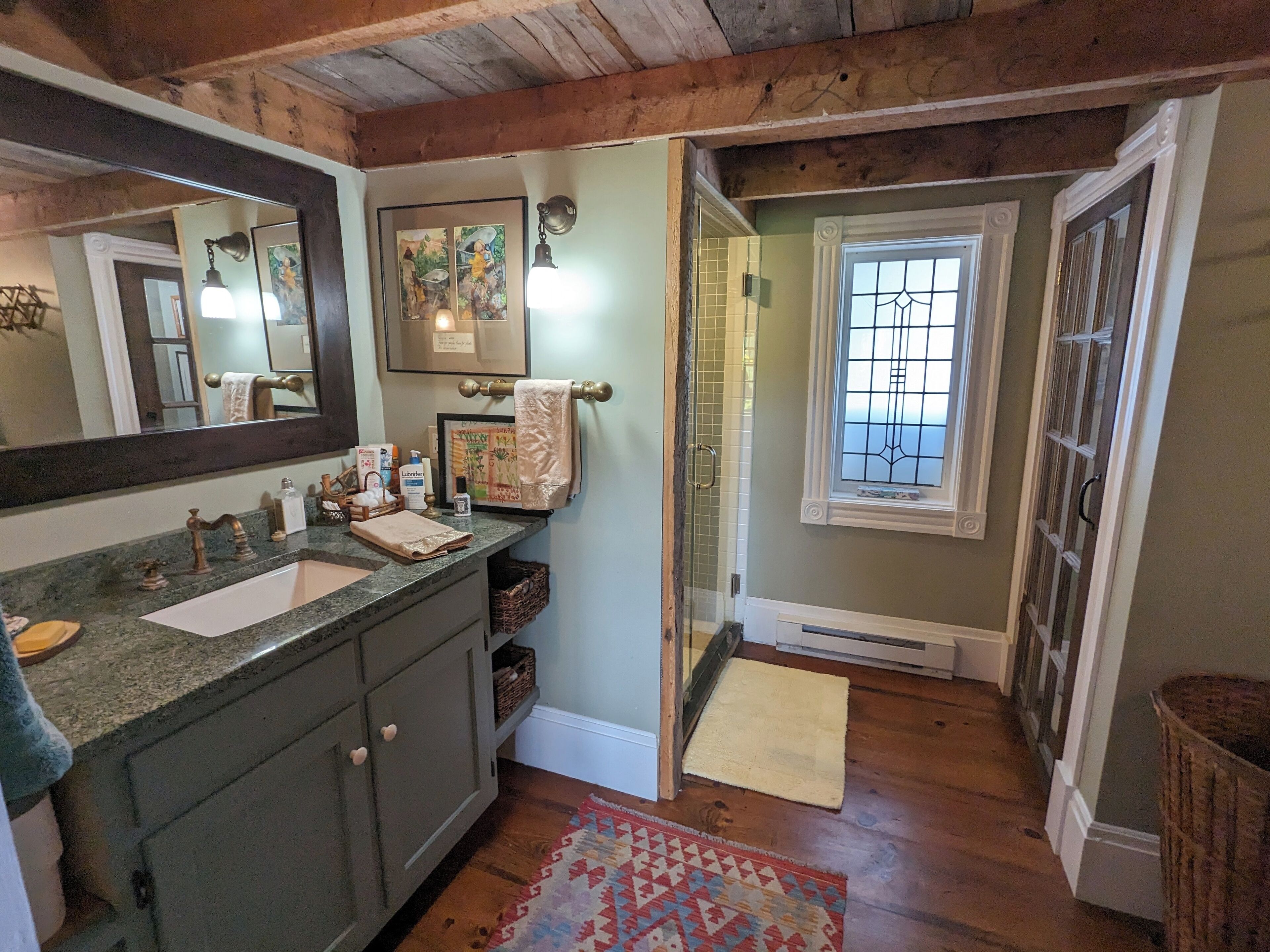 Une salle de bain avec un plafond en bois, un grand miroir, un lavabo et un espace douche.