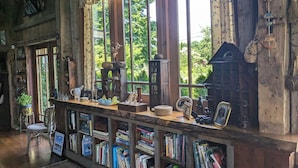 Una habitación rústica de madera con un gran ventanal, estanterías llenas de libros y diversos objetos decorativos.