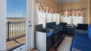 A covered outdoor seating area with wicker furniture and a view of the beach. - Pet-friendly Historic 4BR Home in Illinois (Lynn Center)