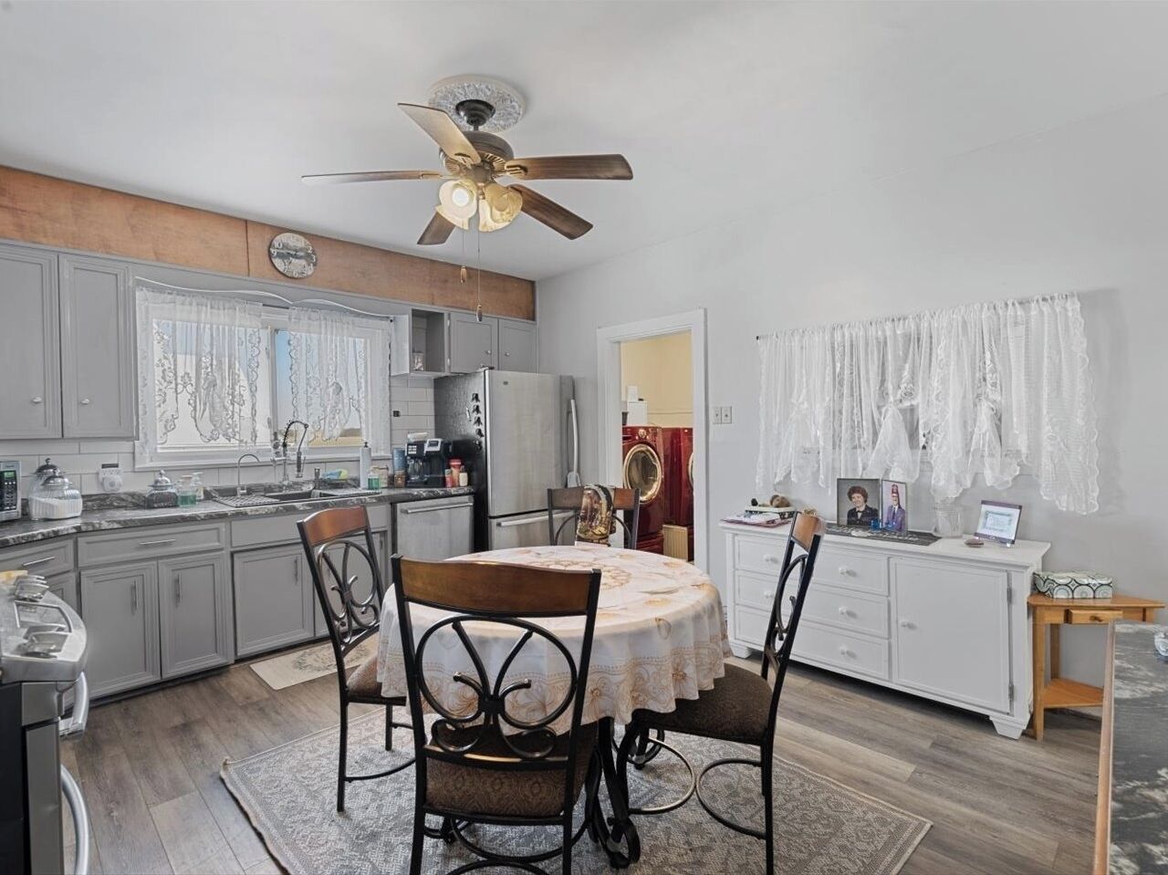 Una cocina compacta con comedor, que incluye un ventilador de techo, un refrigerador y una mesa de comedor con sillas.