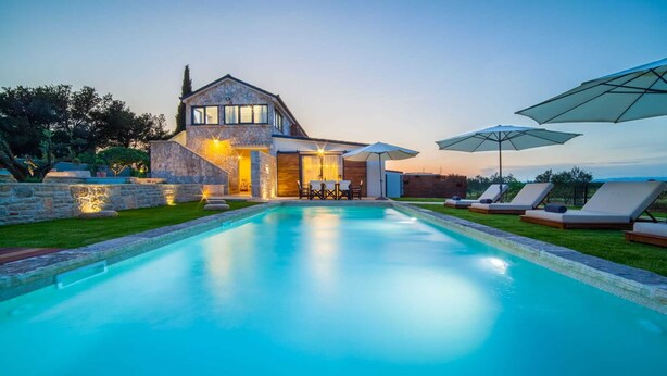 Een modern huis met een zwembad, een stenen gevel en een terras.