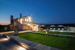 Una casa de piedra con piscina y mobiliario de exterior.