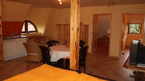 A room with a bed, a dining table with chairs, a kitchen area, and a TV. - Vacation apartment directly at the fishing pond with parking lot and terrace (Wismar)