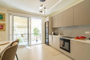 Une cuisine moderne dotée d’une grande fenêtre, d’un coin repas avec des chaises et d’une vue sur le balcon.