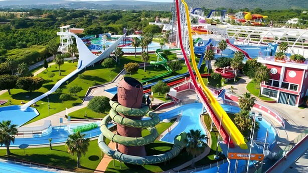 Een waterpark met meerdere glijbanen en een groot zwembad.