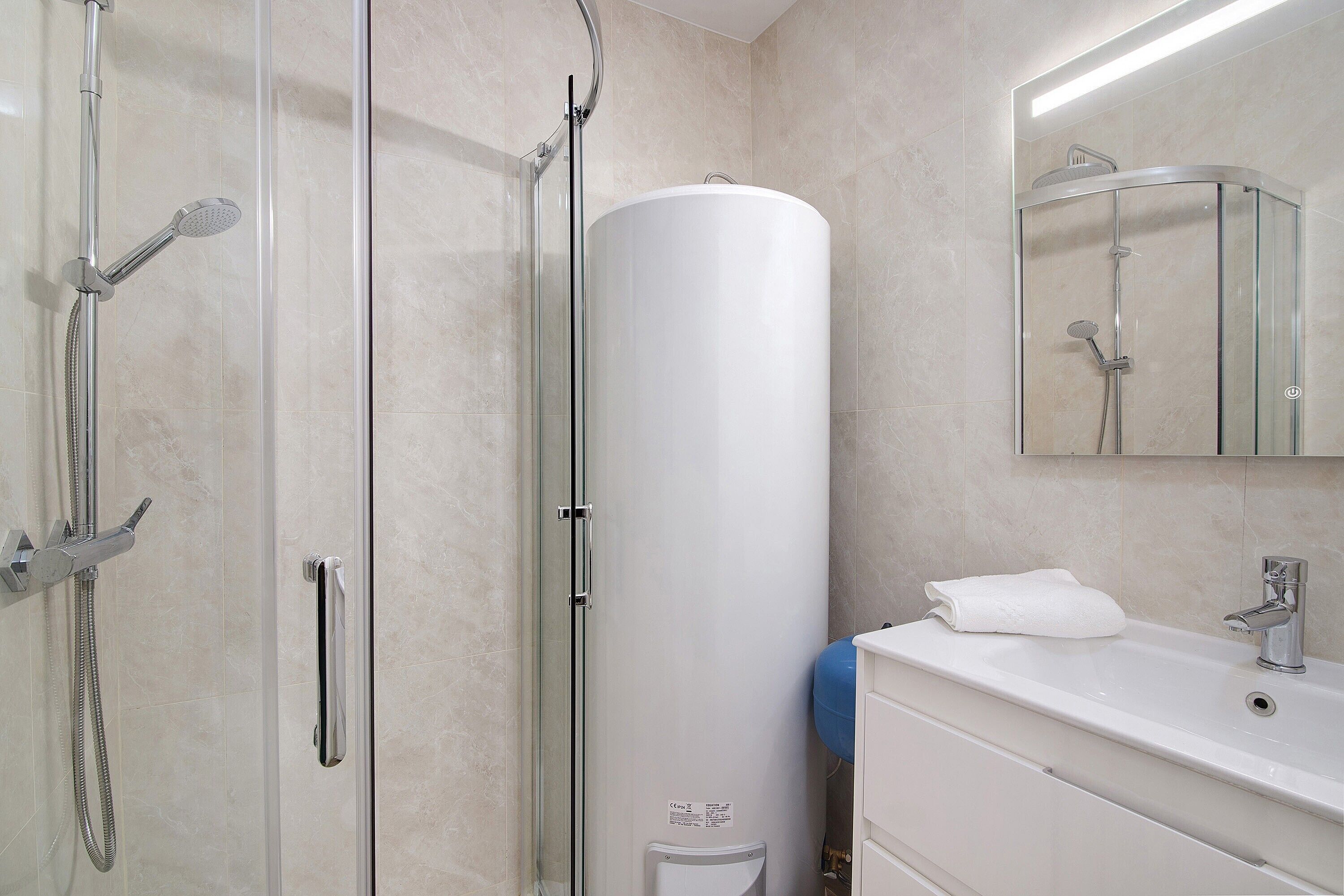 Une salle de bain moderne dotée d’une douche à parois de verre, d’une baignoire sur pieds et d’un meuble-lavabo blanc avec un miroir.