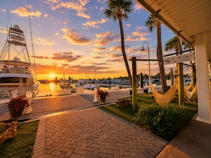A marina with boats, a lifeguard tower, and a sign for 'The Little Dipper Ice Cream Shop' during sunset.