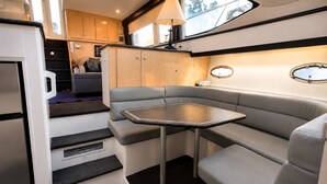 A compact kitchen with a refrigerator, a dining table, and a built-in bench seating area.