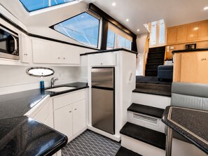 A compact galley kitchen with a built-in refrigerator, a sink, and a window above the counter.