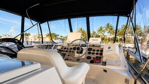 A boat's interior with a steering wheel, control panel, and seating area.