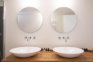 Une salle de bain avec deux miroirs ronds, un meuble-lavabo en bois et un lavabo blanc.