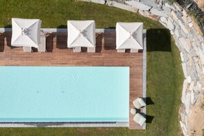 Une piscine sur le toit, agrémentée de trois parasols blancs et de chaises longues.