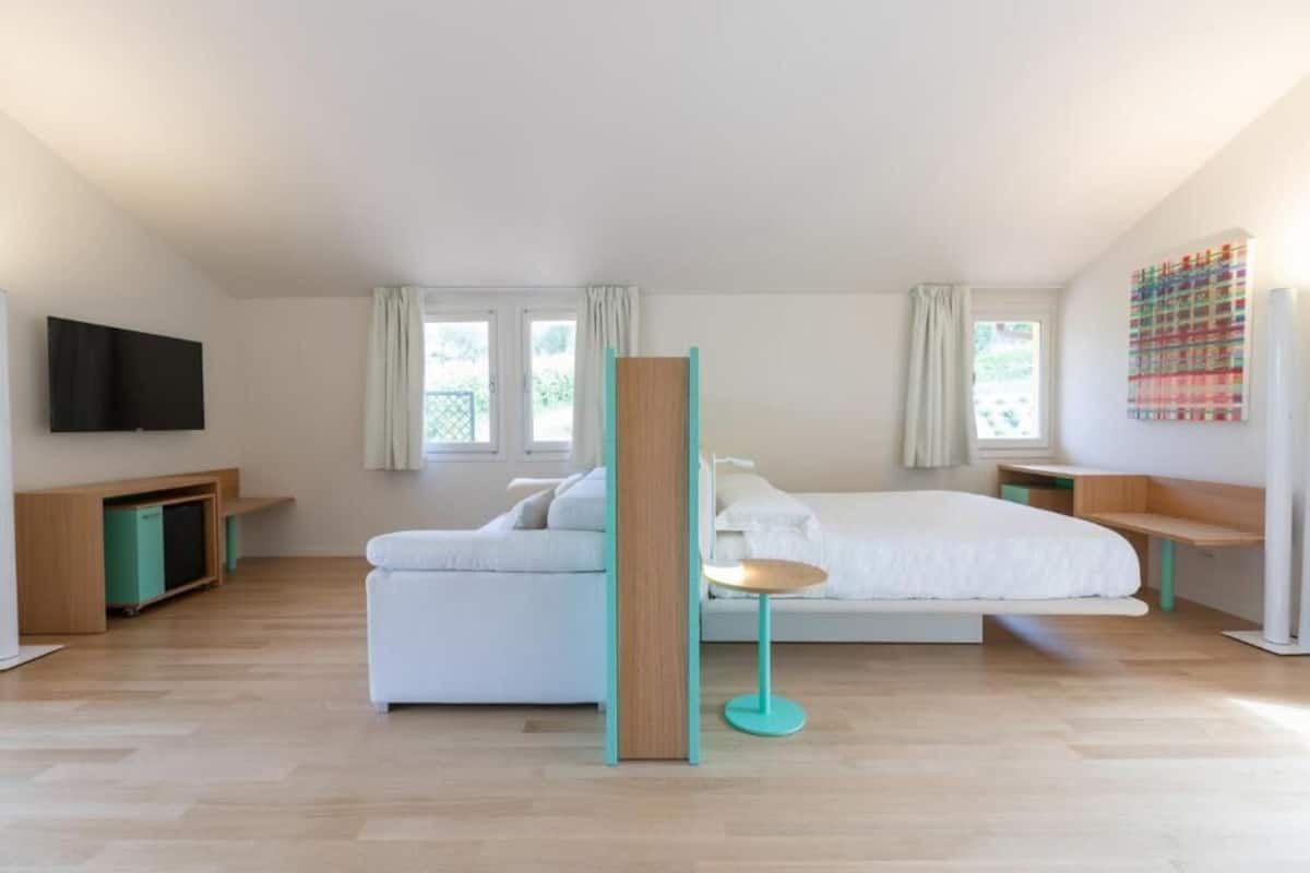 Ein modernes Schlafzimmer mit Bett, Sofa, Fernseher und Schreibtisch.