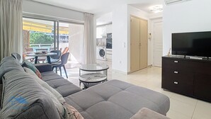 Een moderne woonkamer met een bank, een televisie en een eethoek met een tafel en stoelen.