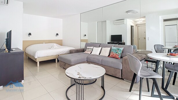 Een moderne hotelkamer met een bed, een bank, een eettafel met stoelen, een televisie en een grote spiegel.