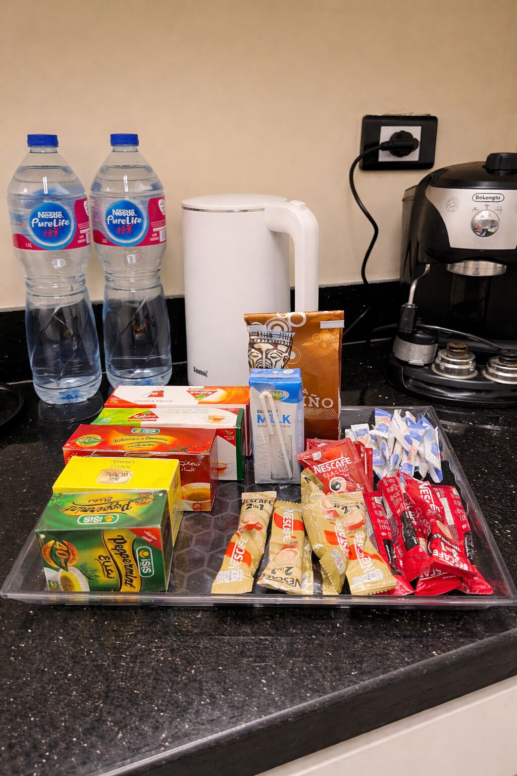 A kitchen counter with various food items, including bottled water, coffee maker, and packaged snacks.