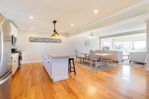 A modern kitchen with a central island, white cabinetry, and a stainless steel refrigerator.