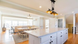 A spacious kitchen with a large island, white cabinetry, and a chandelier. - 5BR/5BA Beachside Newport Home Steps to Beach! (Middletown)