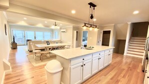 A spacious kitchen with a large island, wooden flooring, and white cabinetry.