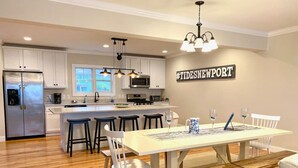A modern kitchen with white cabinets, a stainless steel refrigerator, and a central island with bar stools.
