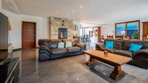 Een moderne woonkamer met twee leren banken, een houten salontafel en een accentmuur van natuursteen.